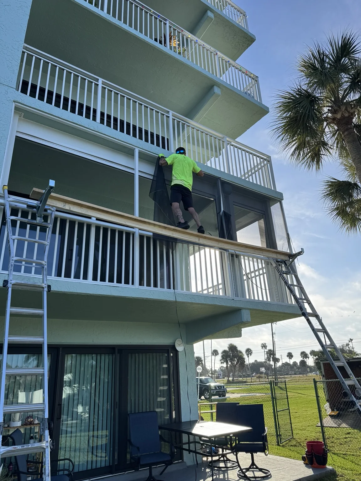 Installing screen panels on the second-floor balcony enclosure.
