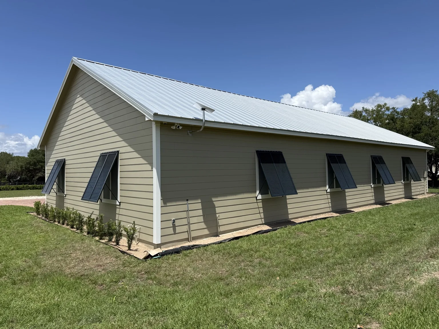 Custom Bahama shutters installed across multiple windows for shade and exterior character.