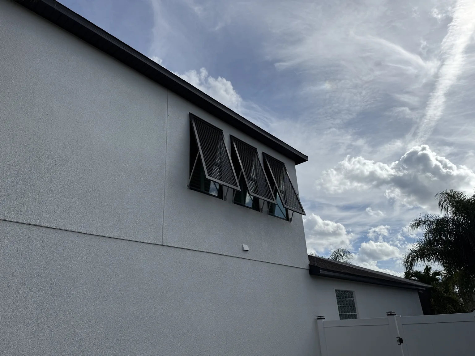 Three-window Bahama shutter installation providing shade while maintaining airflow and visibility.