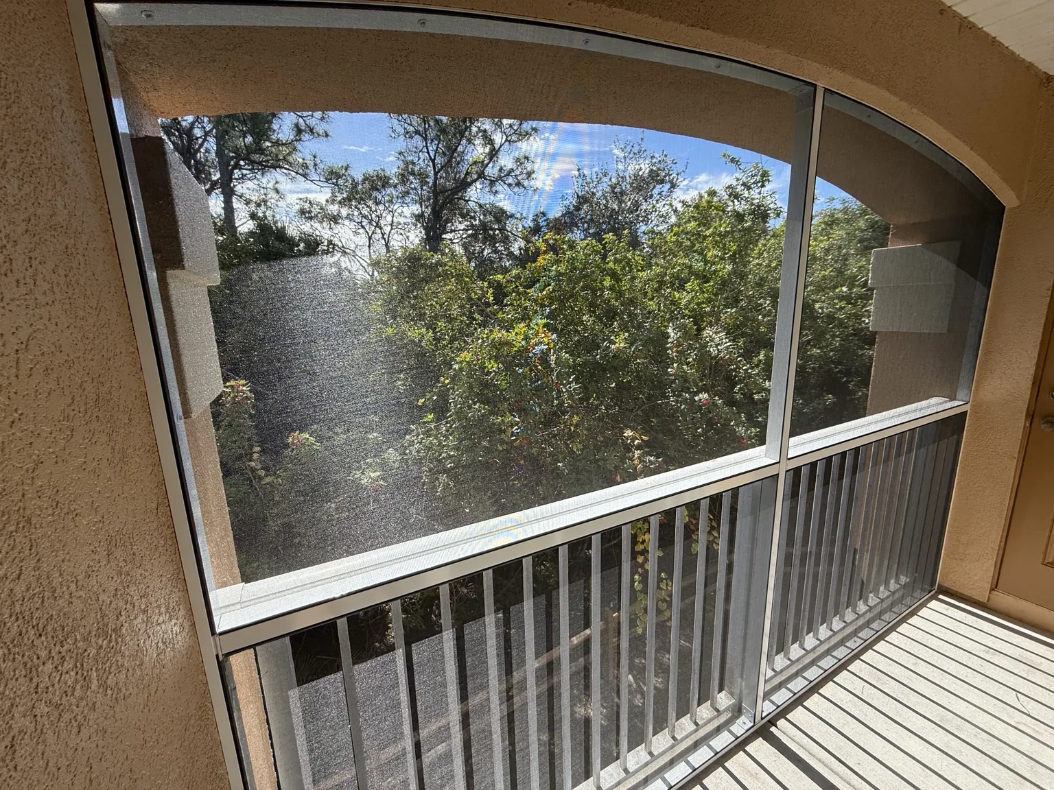 Custom screening fitted around the existing arched balcony opening.