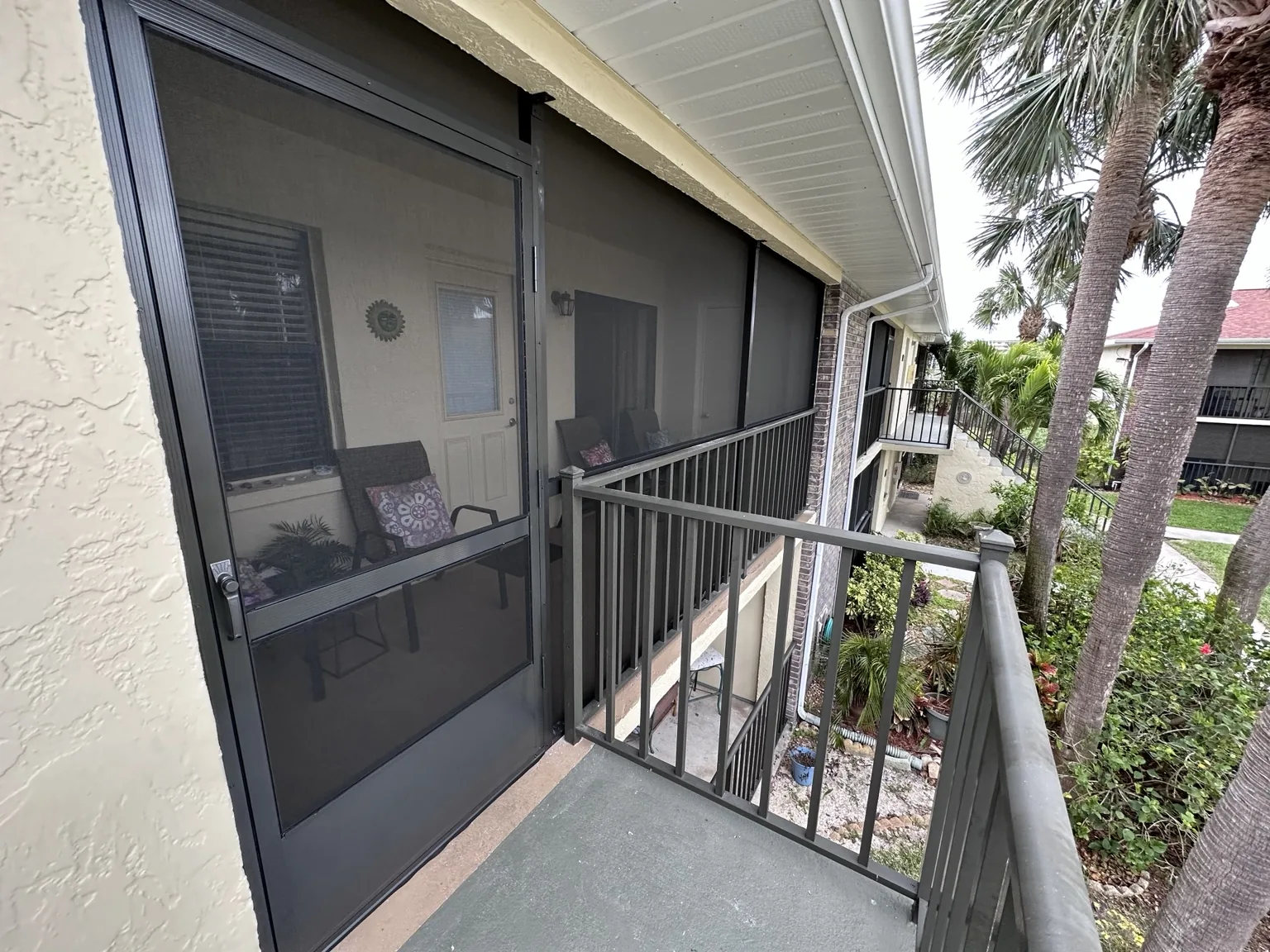 Second-floor balcony enclosed with custom screen walls and access door.