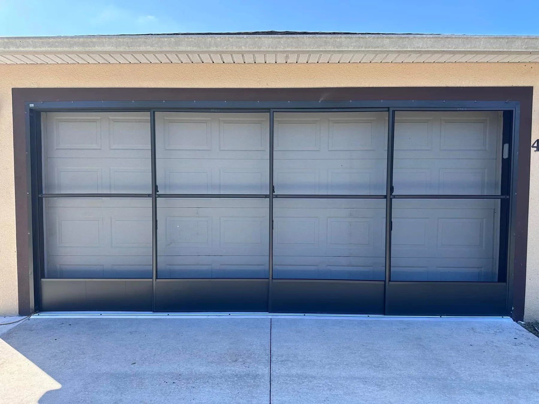 Four-panel sliding garage screen system installed inside the existing opening.