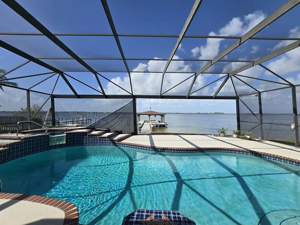 Pool enclosure before repair with a massive screen section missing and the structure leaning to the left.