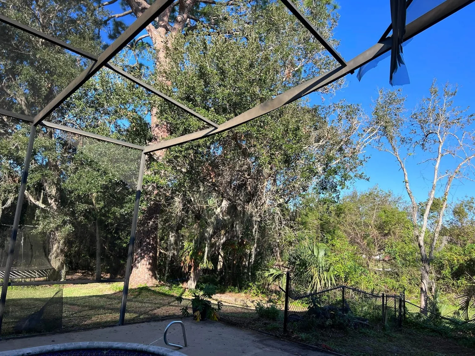 Pool enclosure before repair with damaged roof-screen sections.