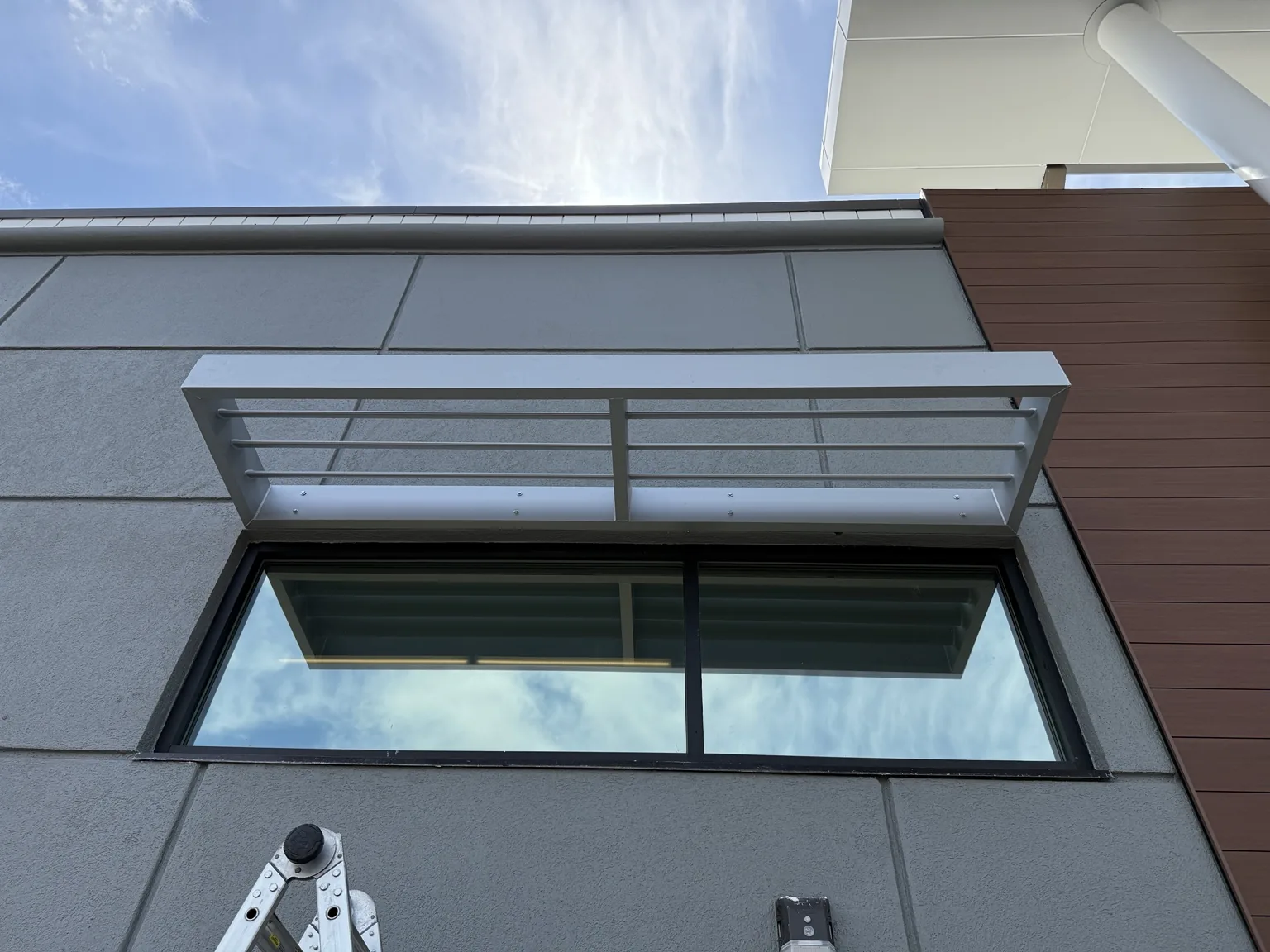 Powder-coated aluminum awning fabricated to fit the window opening and building design.