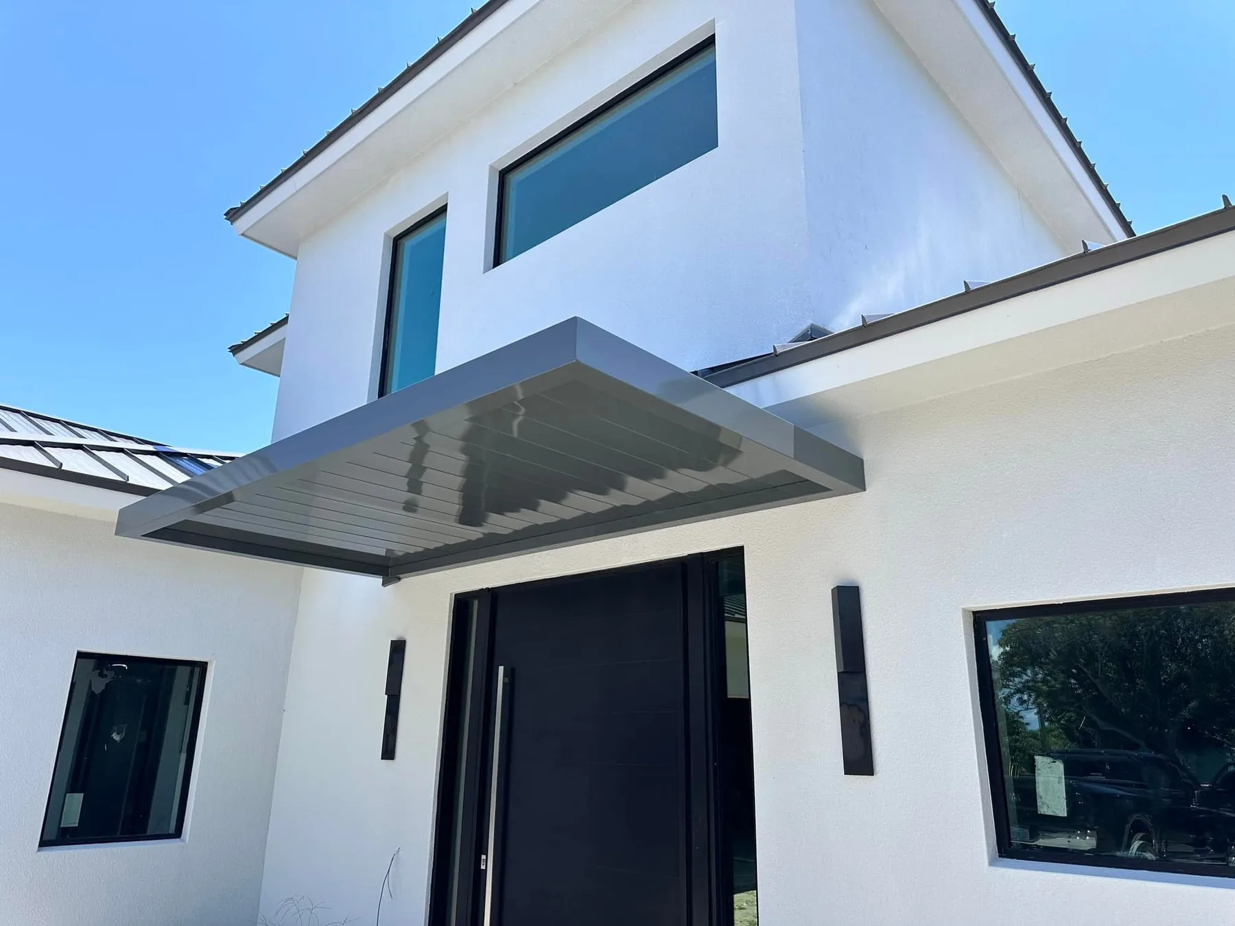 Large custom structural canopy providing shade and weather protection over a primary entry.